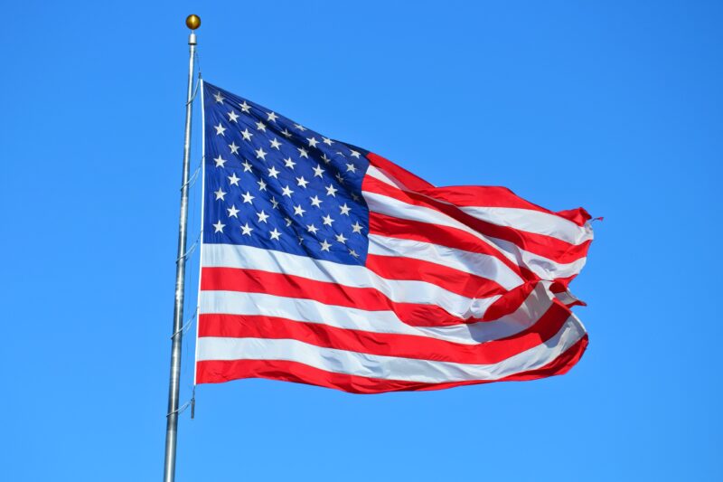 Majestic American Flag Waving in Blue Sky 4K Wallpaper